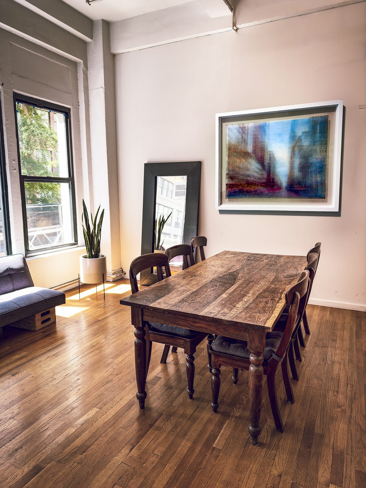 One of the works hung above a long wooden dining table in a sunlit loft