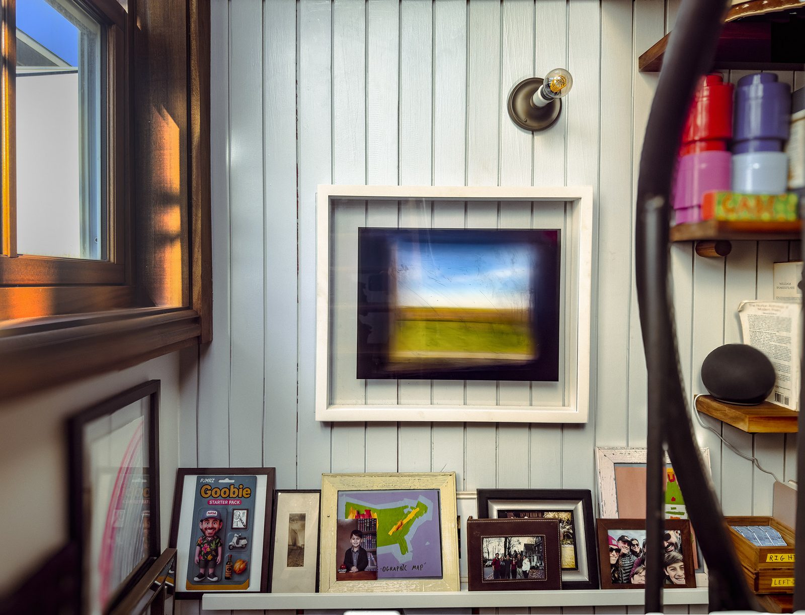 One of the works in a lived-in nook above a shelf of family photos, books, and a child's drawing