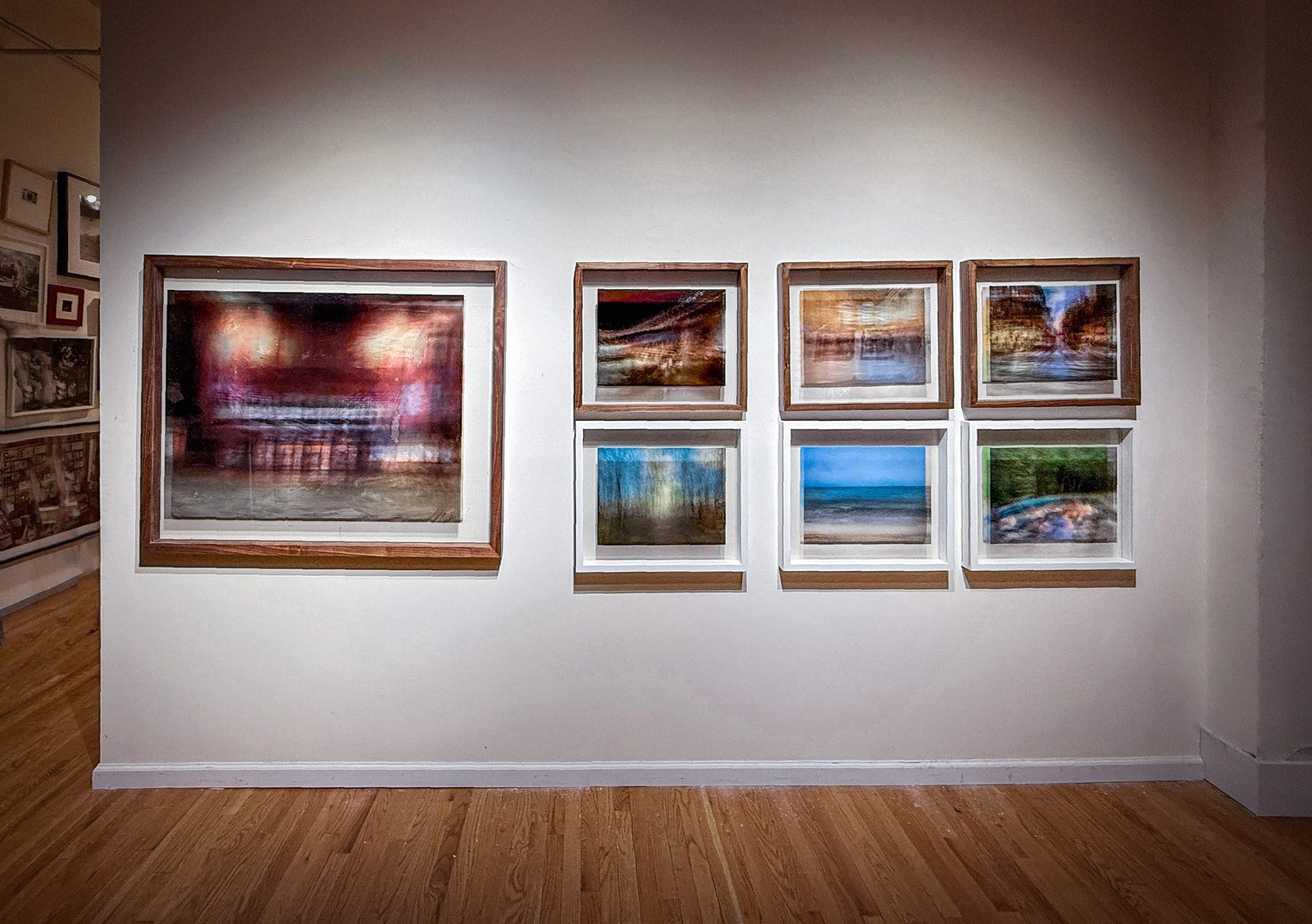 A gallery wall hung with seven of the works — one large piece and six smaller pieces in a grid